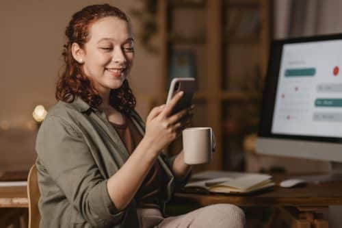 Mulher utilizando o celular para indicar amigos através do Programa Ganhe Mais da Construtora Pride